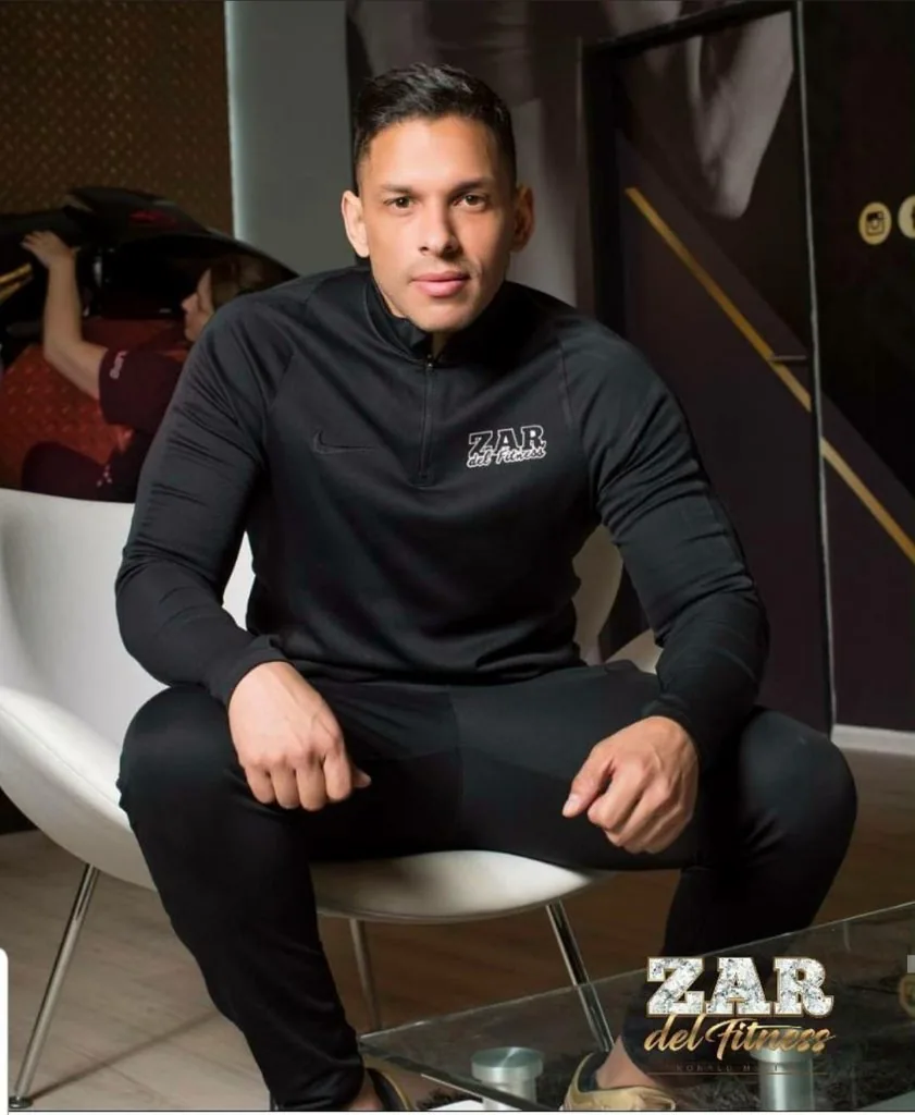 Ronald Medina seated, wearing black Zar del Fitness clothes